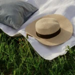 A camping pillow in outdoor with a hat resting on bedsheet