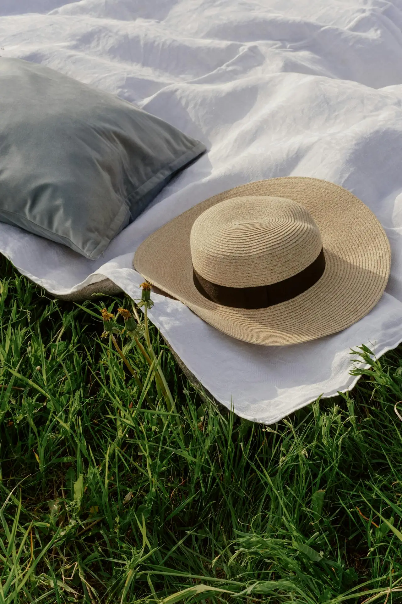 A camping pillow in outdoor with a hat resting on bedsheet