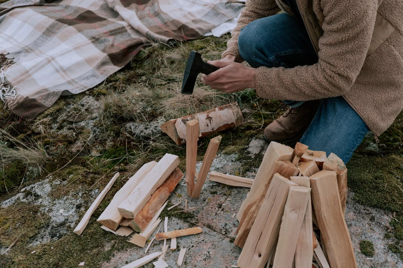 A Person in Brown Coat Cutting the Wooden Log with camping axe