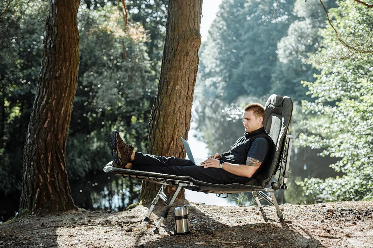 Man in camping wear Sitting working on foldable camping cot