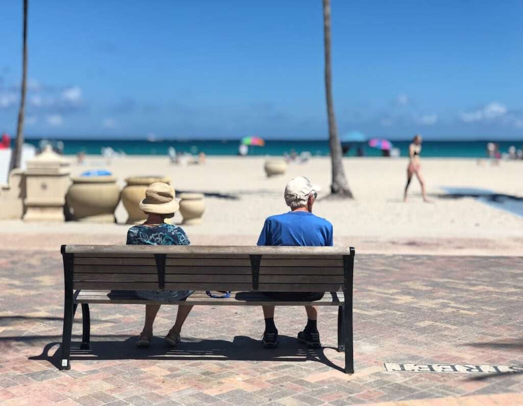 Man and Woman Sitting on Wooden Bench Near Hollywood Beach By Monica Silvestre