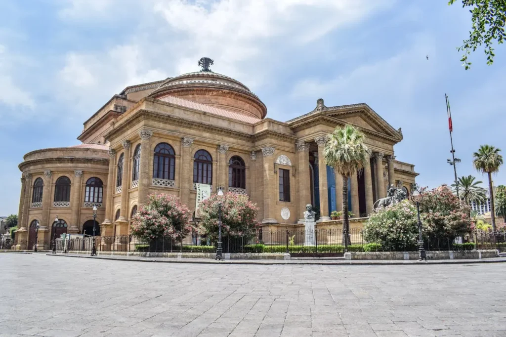 Ancient building of opera house located on well groomed square against blue sky